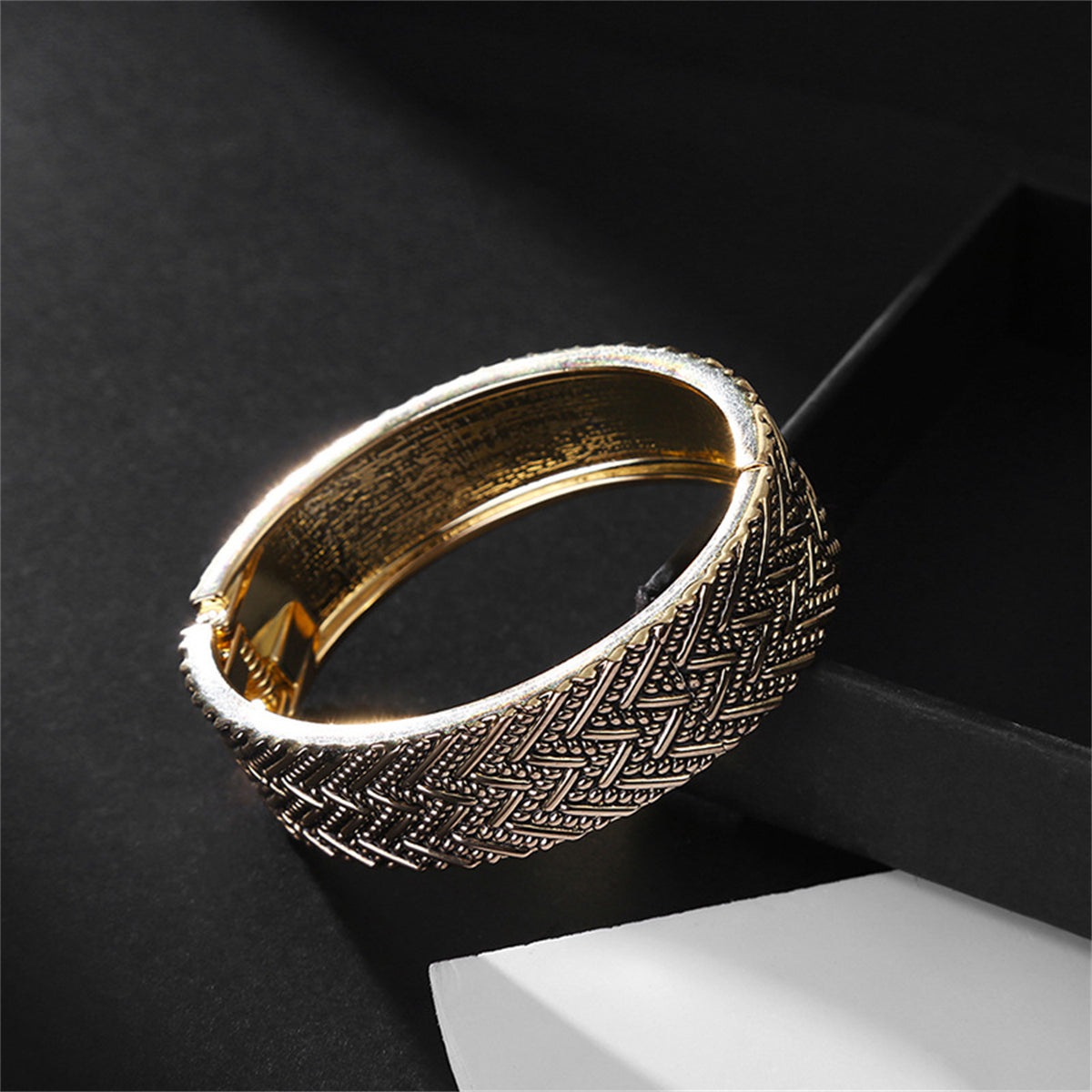 Elegant 18K gold-plated bangle featuring a woven chevron pattern, perfect for adding a touch of sophistication to any outfit.