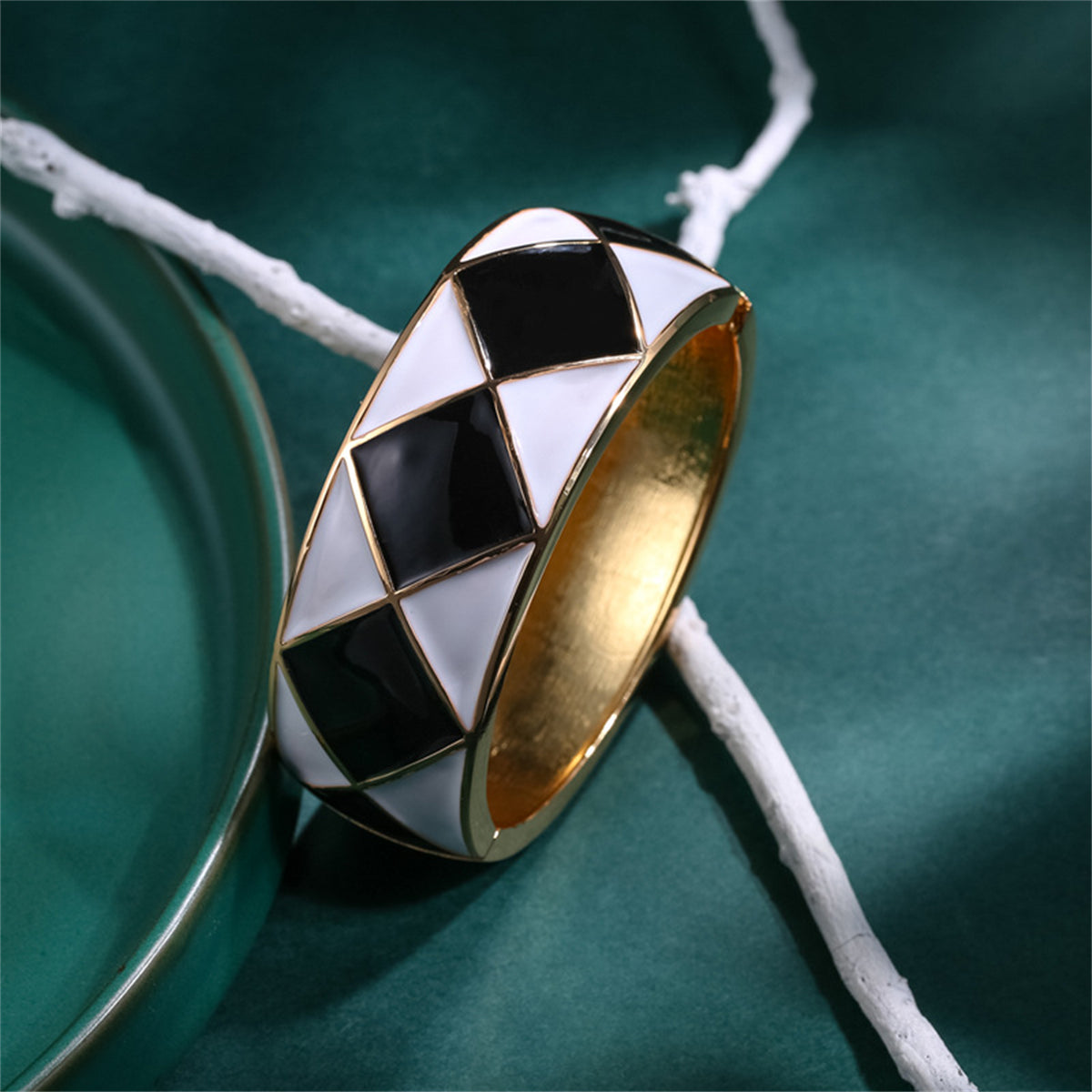 A chic black and white diamond-patterned cuff bracelet, showcasing black enamel and 18K gold-plated rhombus elements.