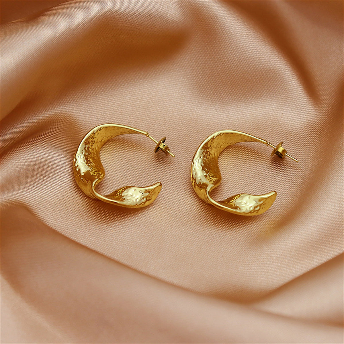 Eye-catching 18K gold-plated curved huggie earrings, designed to elevate your accessory game with their sleek silhouette.