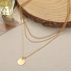 Chic three-layer necklace in 18K gold plating, showcasing a disc pendant and two chains for a fashionable statement.