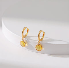 Elegant yellow gold-plated huggie earrings adorned with a round cut yellow crystal, perfect for any occasion.