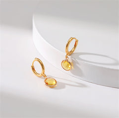 Stunning yellow gold-plated earrings with a round cut yellow crystal, showcasing a blend of luxury and style.