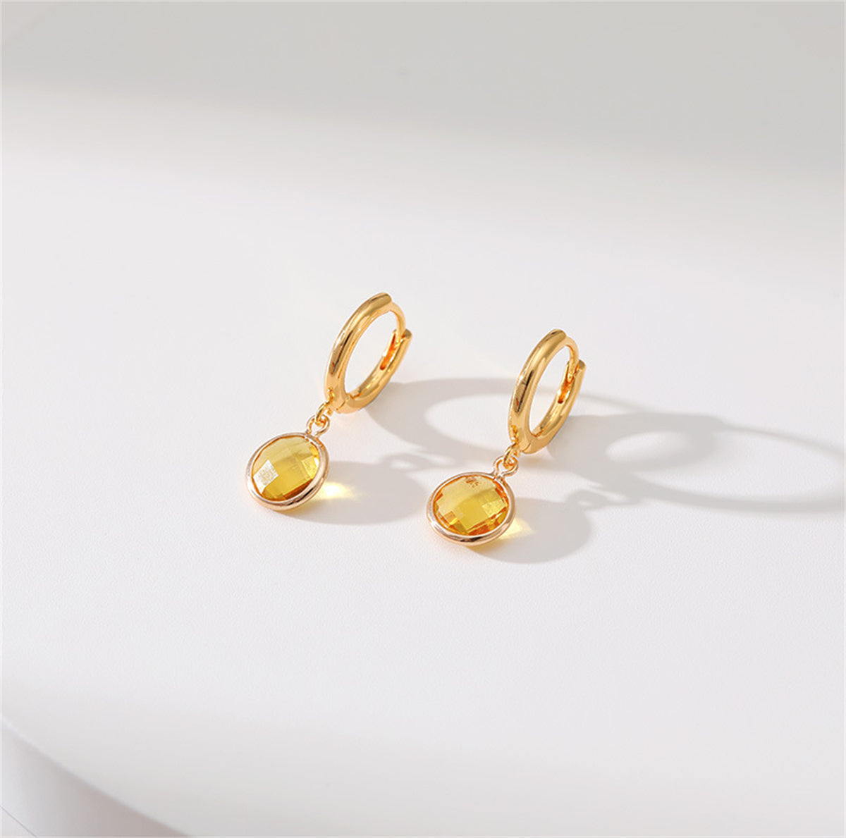 Beautiful yellow gold-plated huggie earrings with a round cut yellow crystal, ideal for enhancing any outfit.