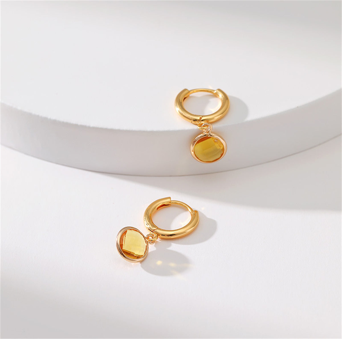 Chic yellow gold-plated earrings featuring a round cut yellow crystal, offering a touch of elegance and glamour.