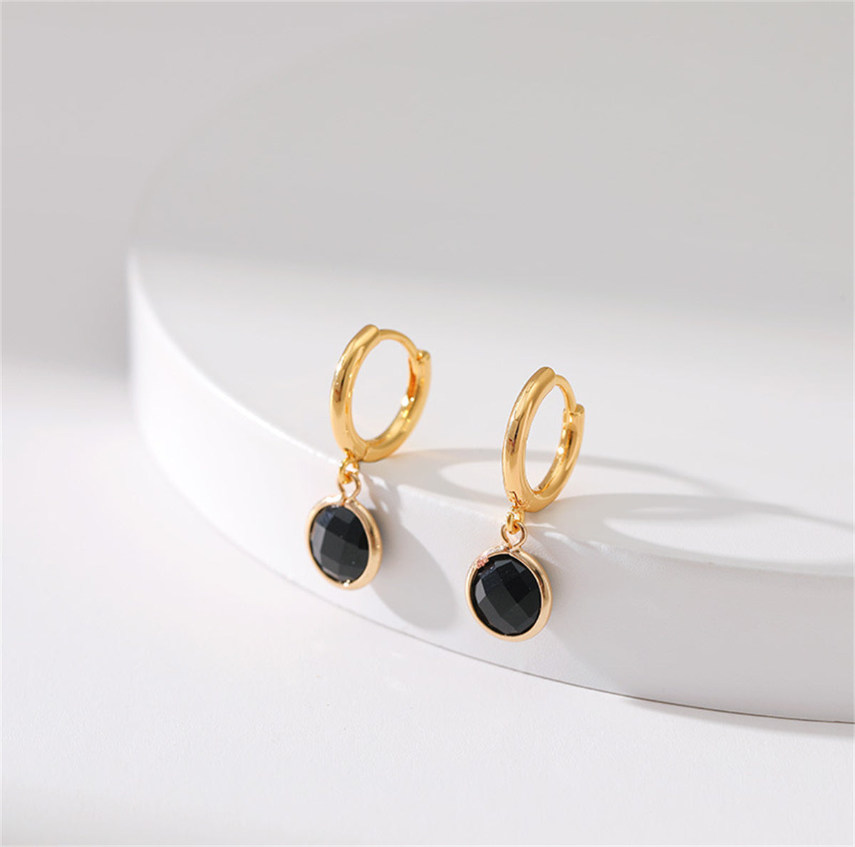 Elegant black crystal huggie earrings, beautifully crafted in 18K gold plating for a sophisticated look.