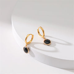 Stylish black crystal hoop earrings, designed as round huggies and plated in 18K gold for a luxurious touch.