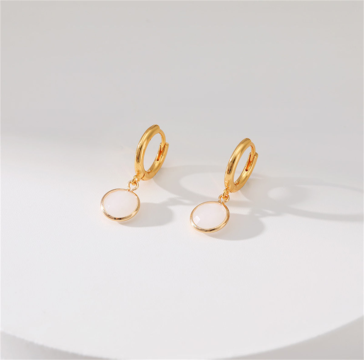 Chic gold-plated huggie earrings set with white crystal, offering a touch of elegance to any outfit.