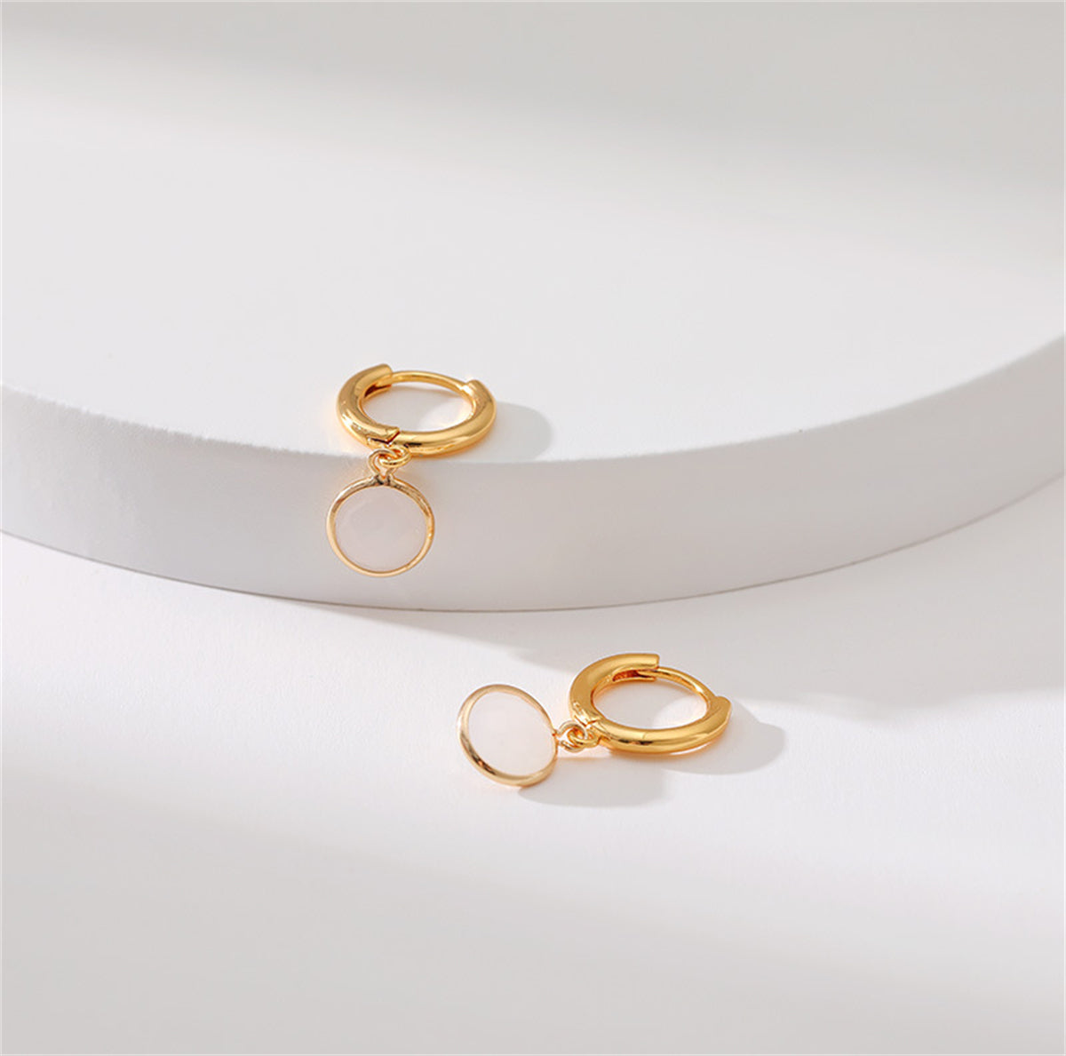 Stylish round huggie earrings in gold-plating, featuring white crystal for a modern and elegant accessory.