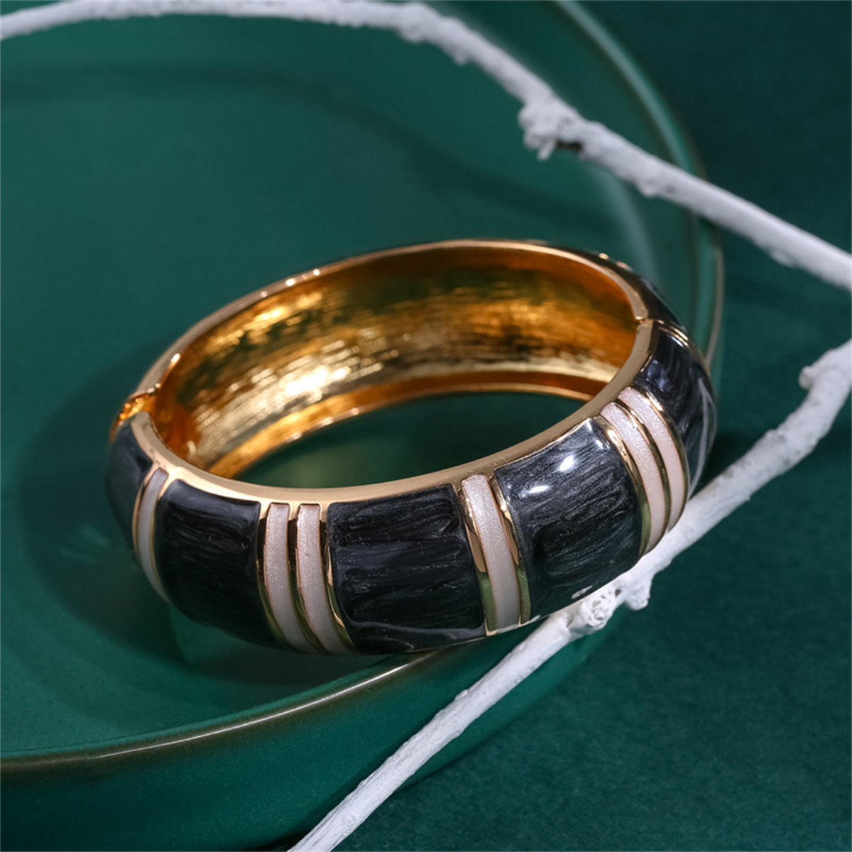 Black and white bracelet showcasing gold and white stripes, designed as a bamboo bangle with black enamel and 18K gold plating.