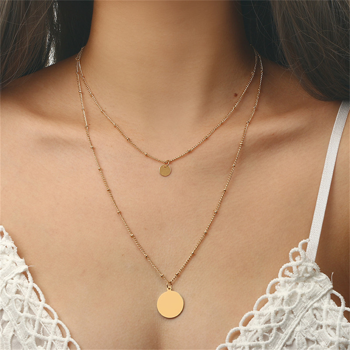 Elegant 18K gold-plated layered necklace featuring two shimmering gold disc pendants on a delicate chain.